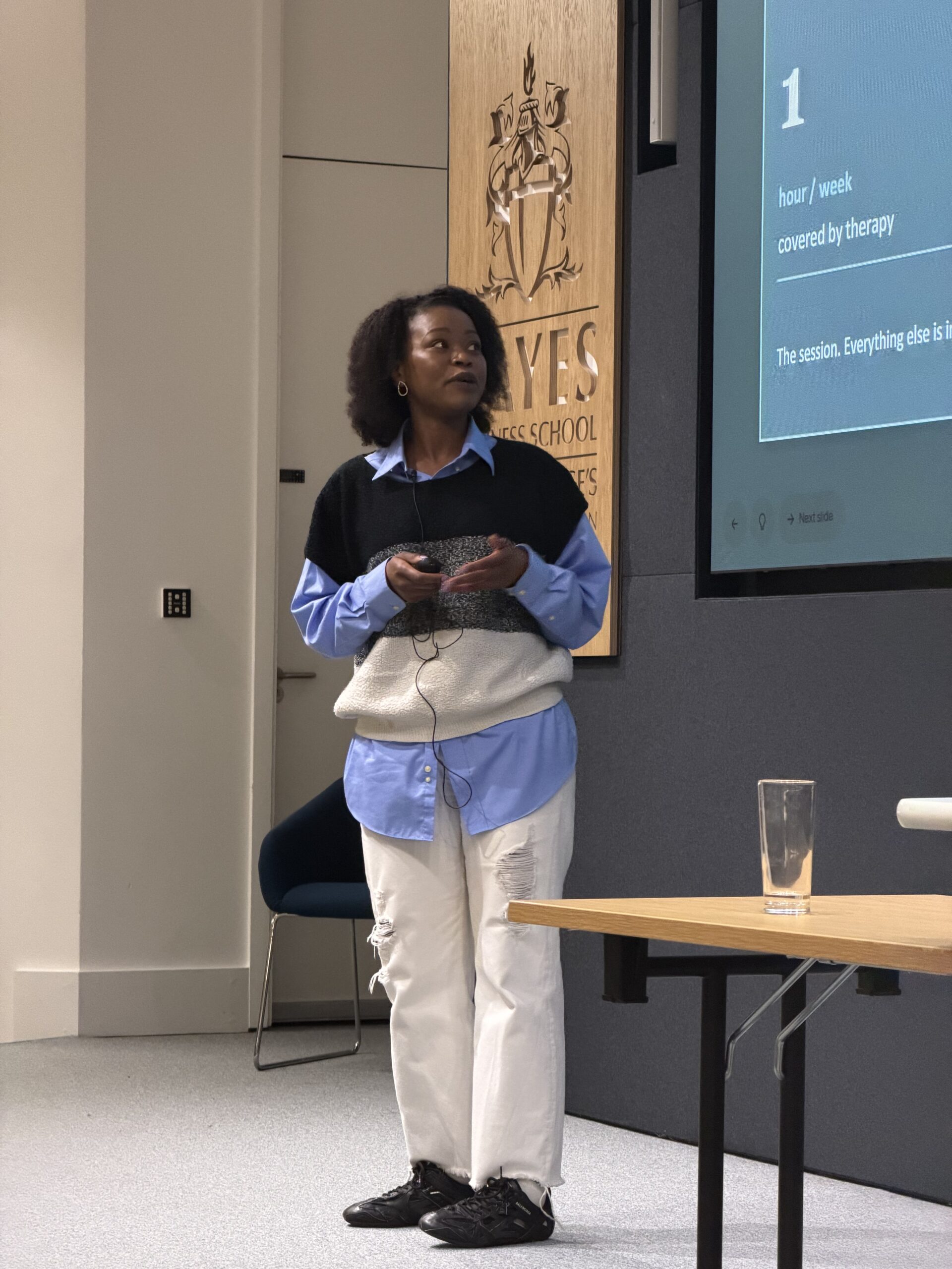 Image of Winnie Akadjo on a stage, presenting at Bayes Business School